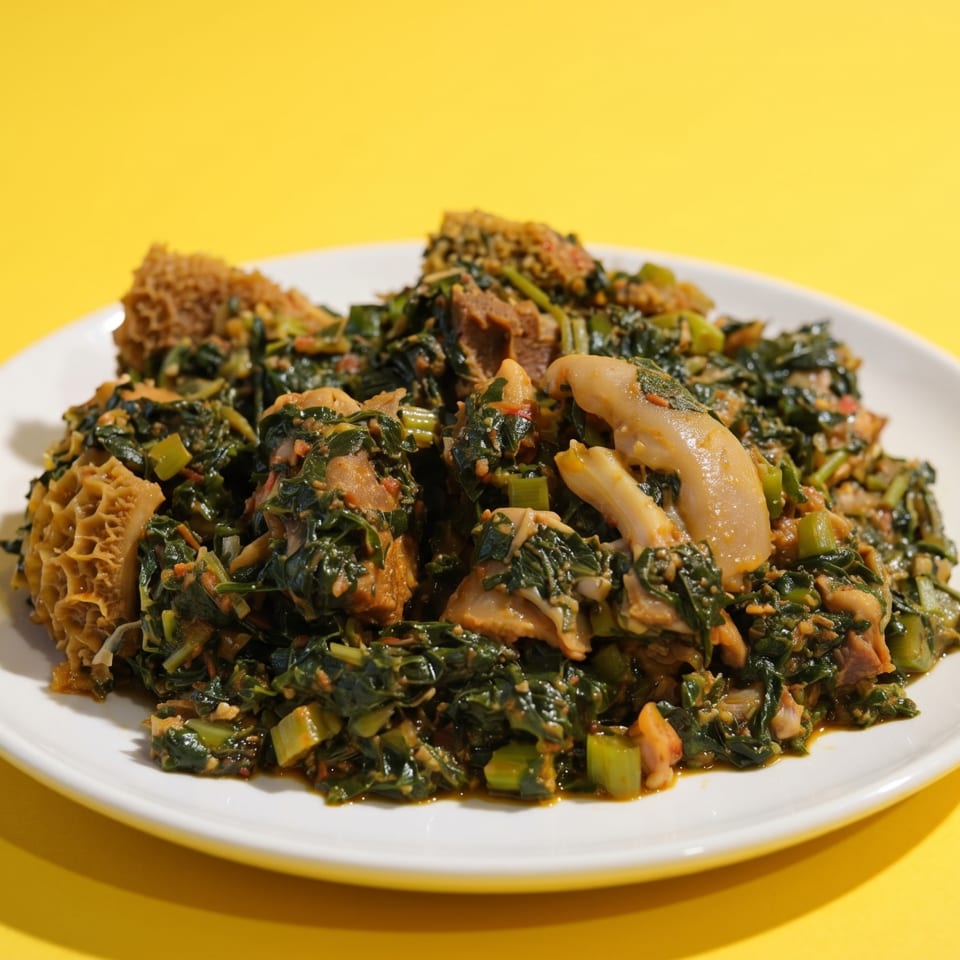 A white plate holds a vibrant green stew with meat and tripe against a bright yellow background.